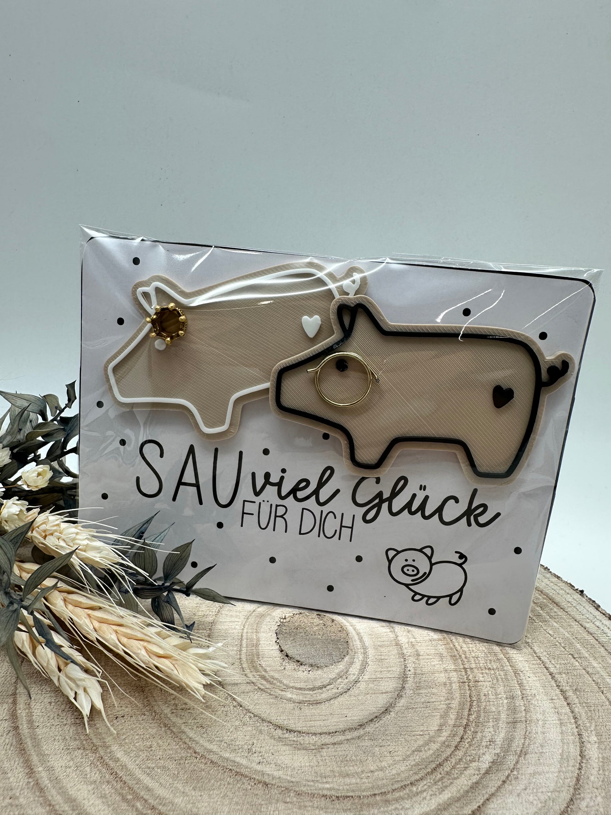 Zwei dekorative Glücksschweinchen mit goldener Krone und Brille auf Karte mit Aufschrift „Sau viel Glück für dich“, perfektes Geschenk für Silvester oder Geburtstag.
